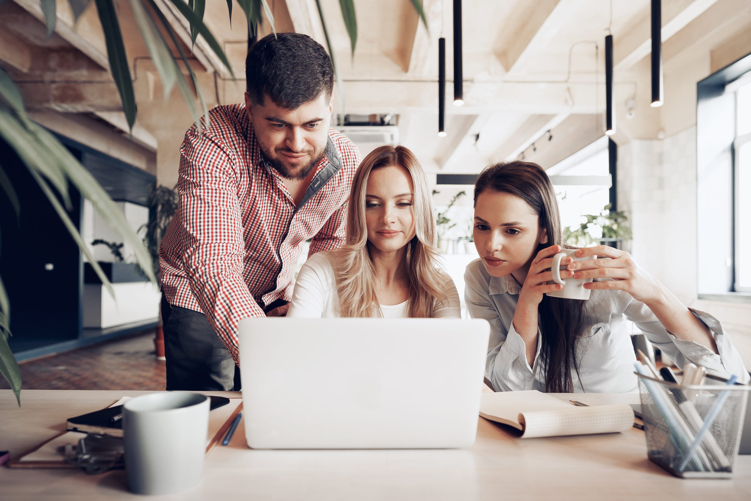 Two female and one male business partners looking at computer screen and discussing their project Teambesprechung vor dem Event